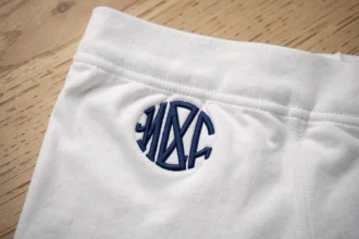 Boxer personnalisé plié avec logo brodé sur la ceinture, posé sur une surface en bois clair